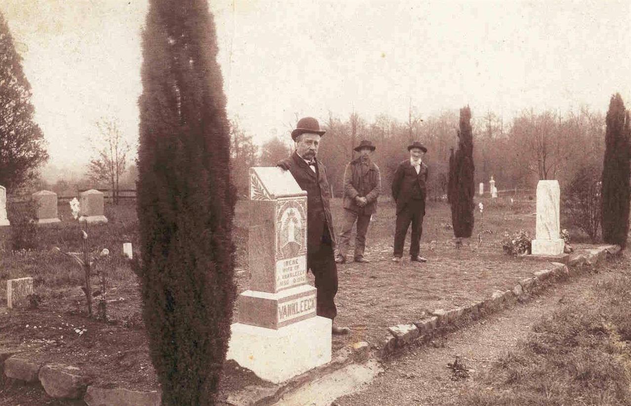 Jeremiah Van Kleeck standing beside the headstone of Irene Van Kleeck.